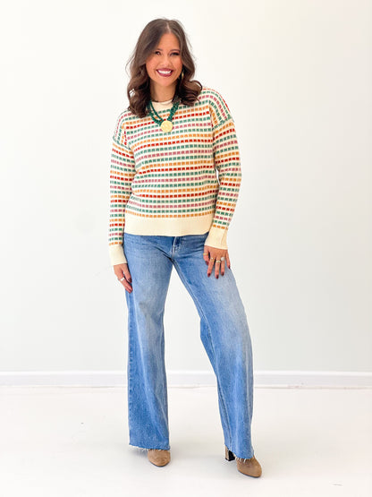 Multi-color striped sweater with crew neck and ribbed cream bottom hem, long sleeves