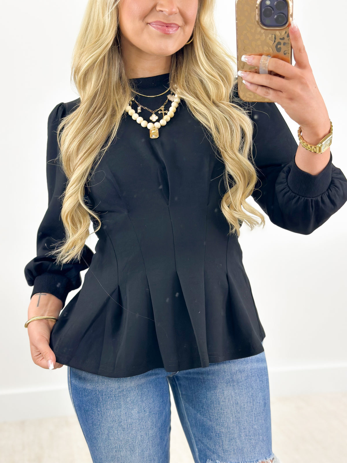 Black pleated flare top with ribbed knit trim at neckline and cuffs