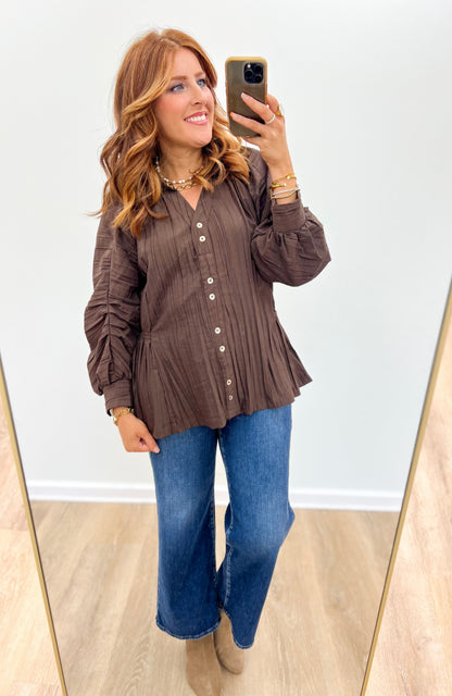 Brown ruched button-up V-neck top with long puff sleeves and gathered ruffle hem