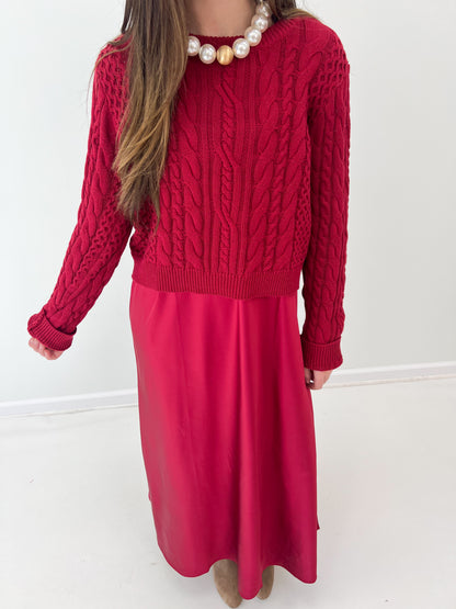 Burgundy knit sweater dress with cable pattern bodice and flowing midi skirt.