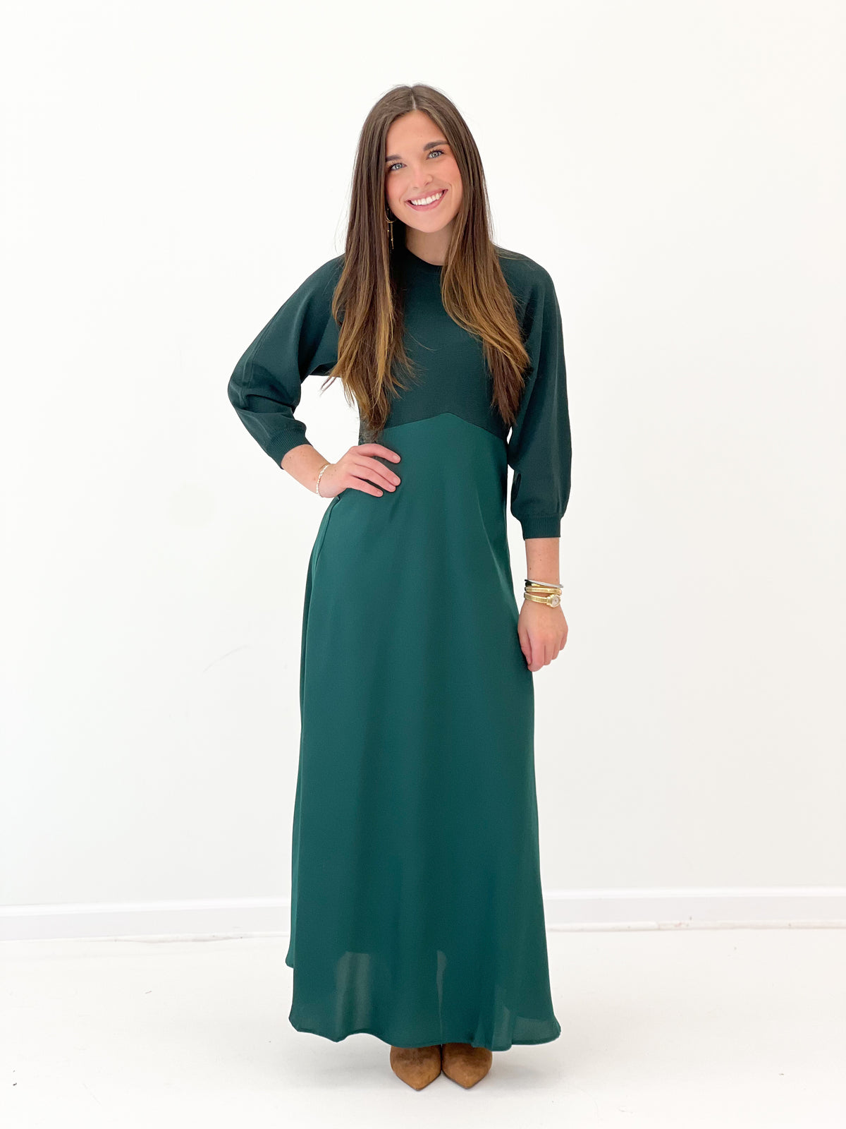 Dark green long-sleeve sweater dress with crew neck, defined waist, and flowing skirt