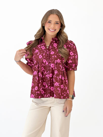 Burgundy floral short-sleeve blouse with button front and stand collar.