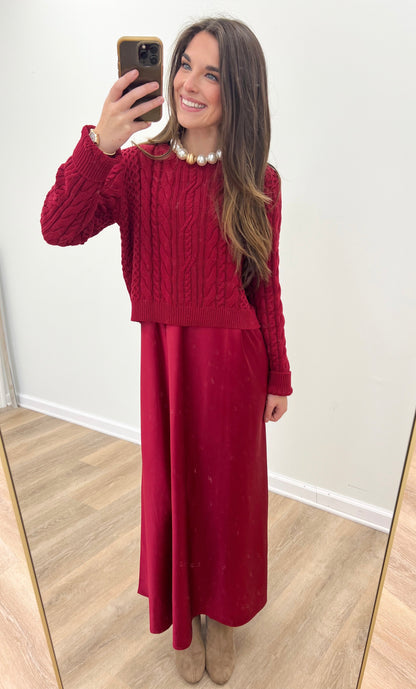 Burgundy sweater dress with textured knit top and solid midi skirt; pearl collar detail.