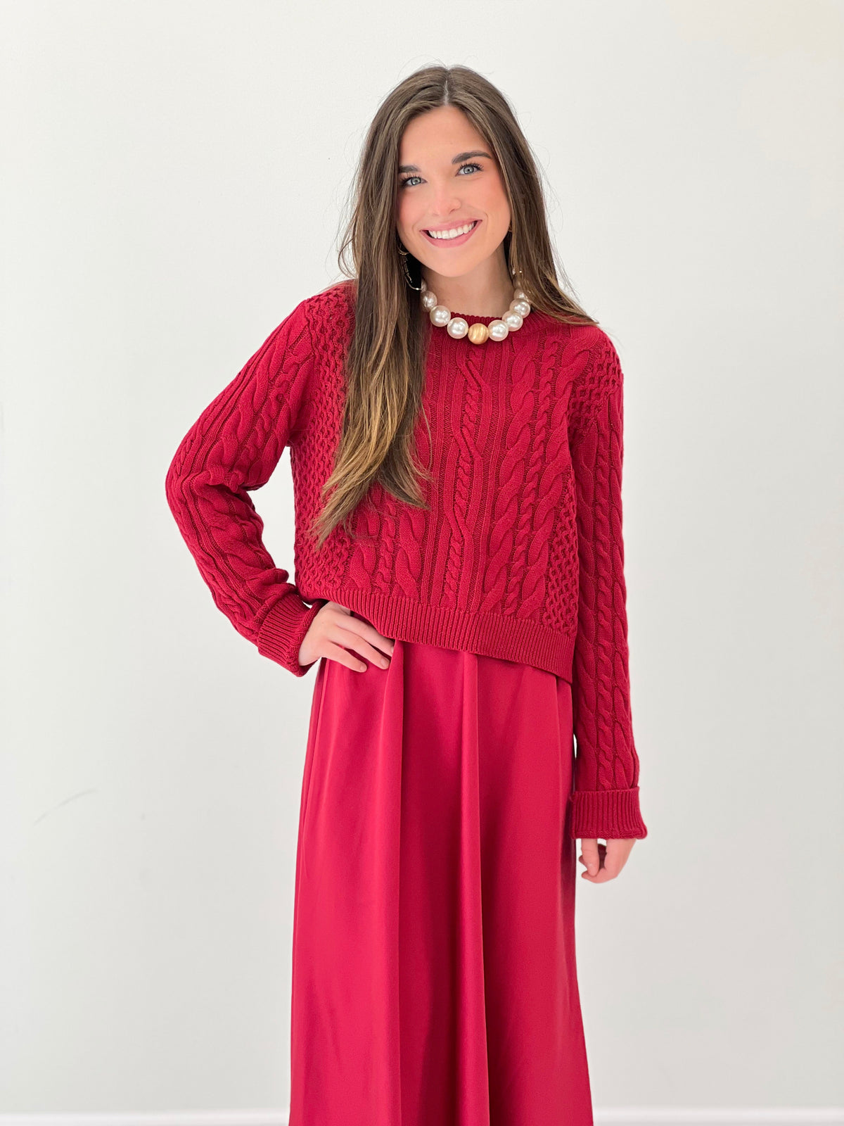 Burgundy cable-knit bodice sweater dress with gathered midi skirt and long sleeves.