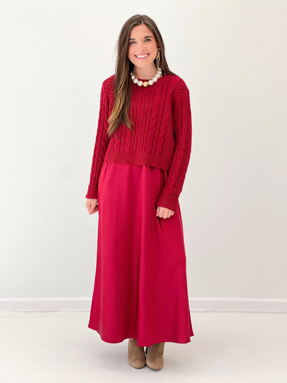 Burgundy long-sleeve sweater dress with cable knit upper and knee-length? midi skirt.