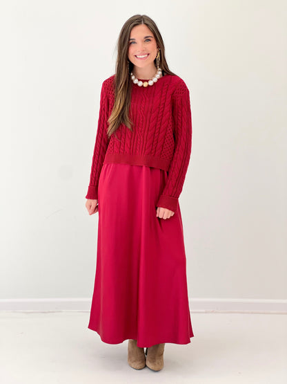 Burgundy long-sleeve sweater dress with cable knit upper and knee-length? midi skirt.