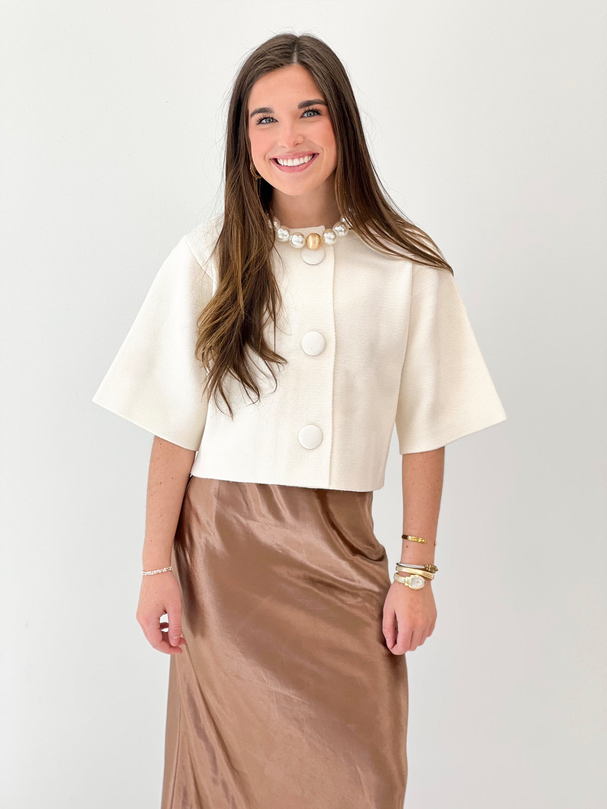 Cream short-sleeve button-front sweater jacket, cropped, with round button placket