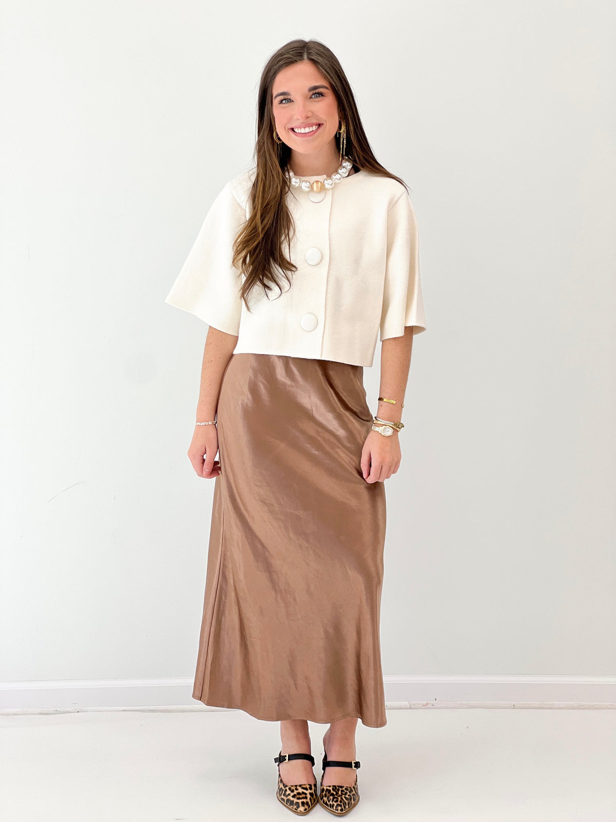 Cream short-sleeve button-front sweater jacket, front button placket and V-shaped collar