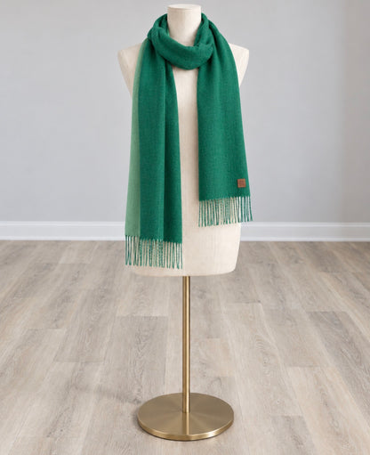 Solid green wool-feel scarf with fringed ends and a small label