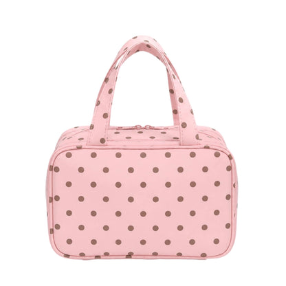 Pink travel makeup bag with brown polka dots, top handles, and a zip-around closure