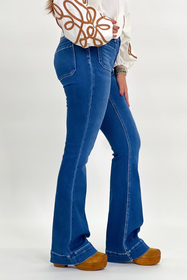 Mid-rise flare jeans side view with stitched seams and button closure, dark blue