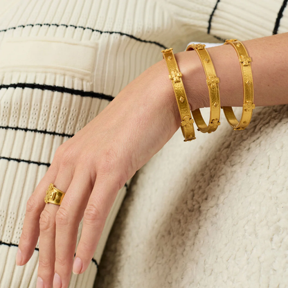Gold-tone bangle bracelet on wrist with small cross engravings and open links