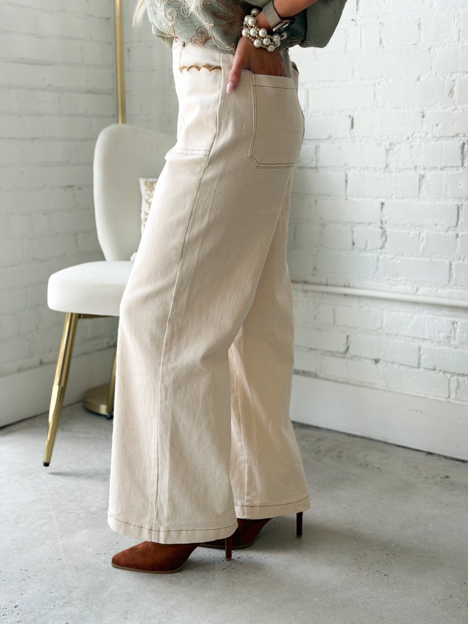 Off white pants with scallop edged pockets at the hip