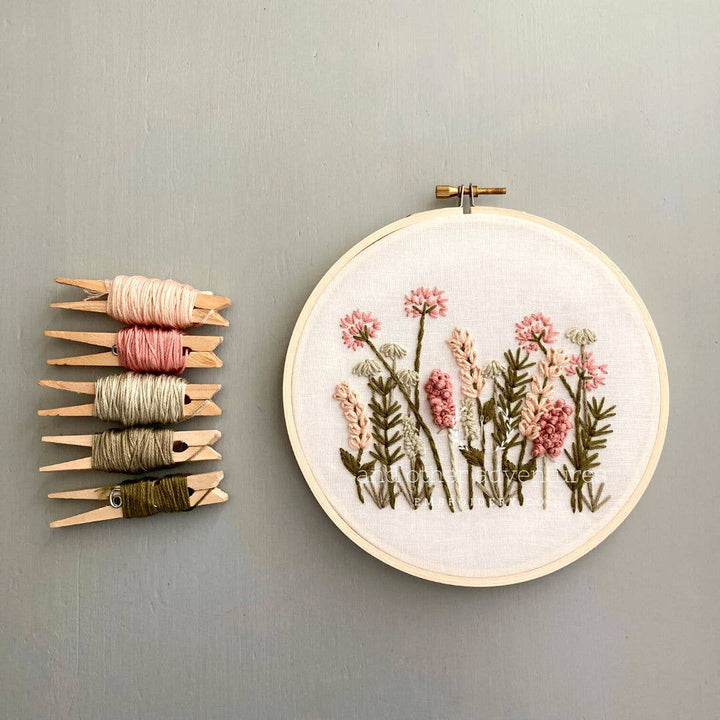 Hand embroidery kit: round hoop with pink and olive floral stitches; thread spools included