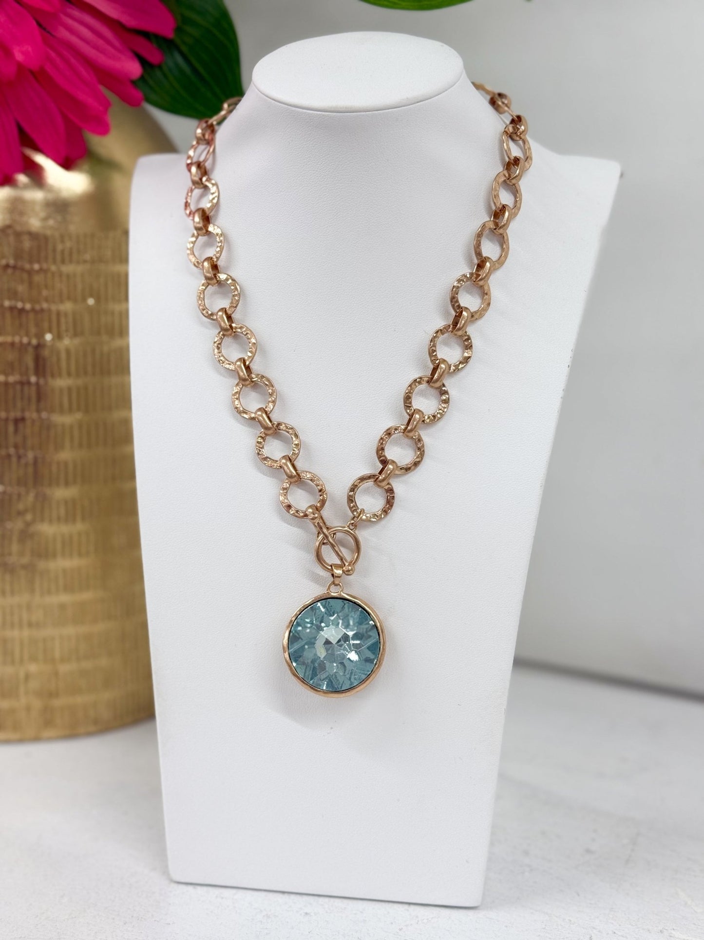 Faceted round glass stone suspended from a chain