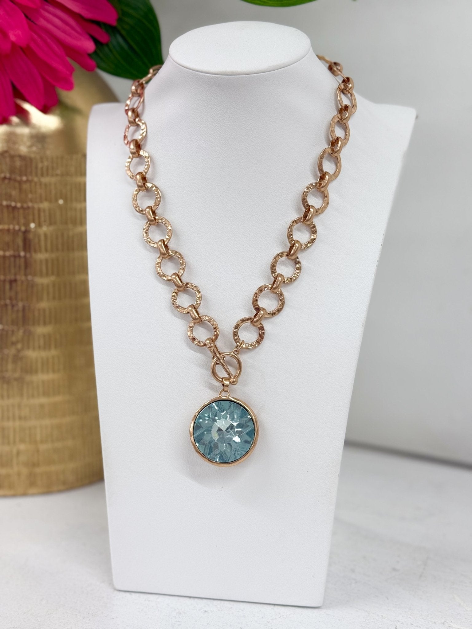 Faceted round glass stone suspended from a chain