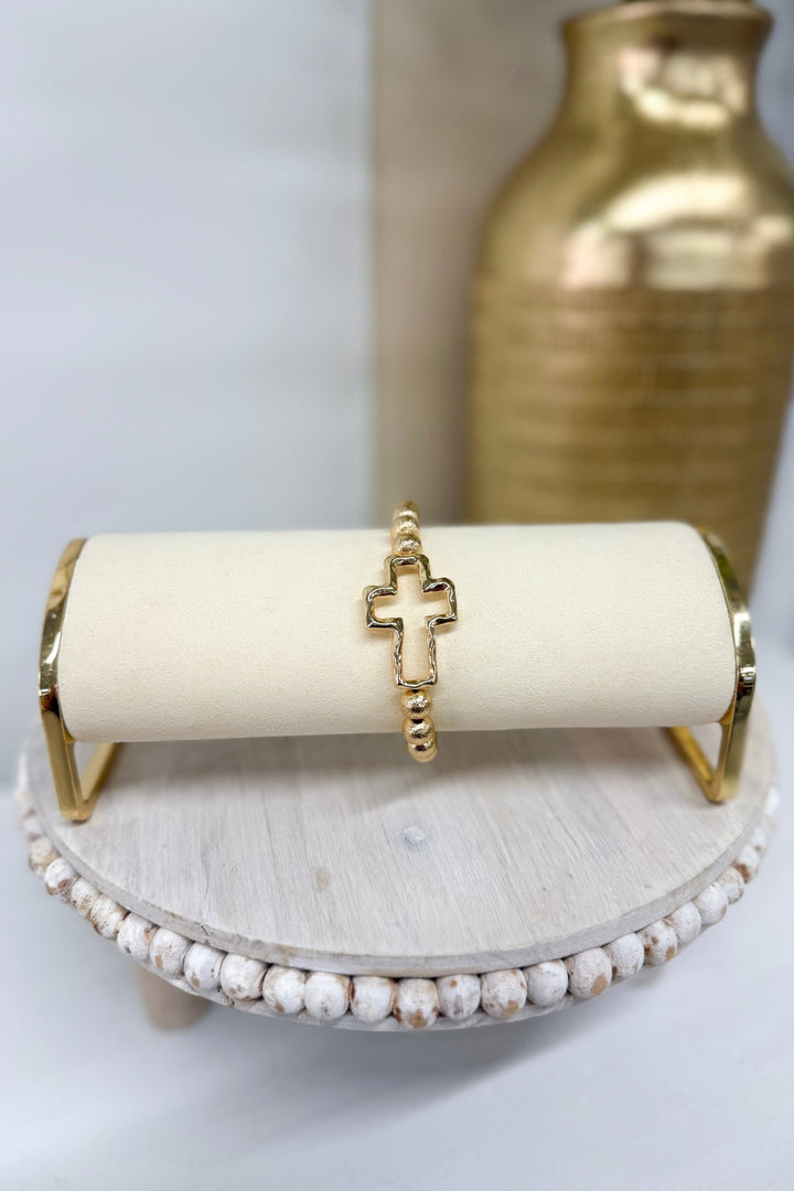 Gold textured metal bracelet with a cross accent