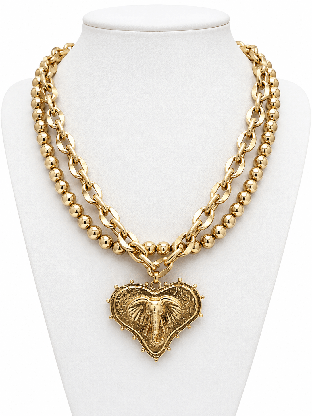 Layered necklace with a heart pendant and mascot charm in worn gold