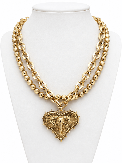 Layered necklace with a heart pendant and mascot charm in worn gold