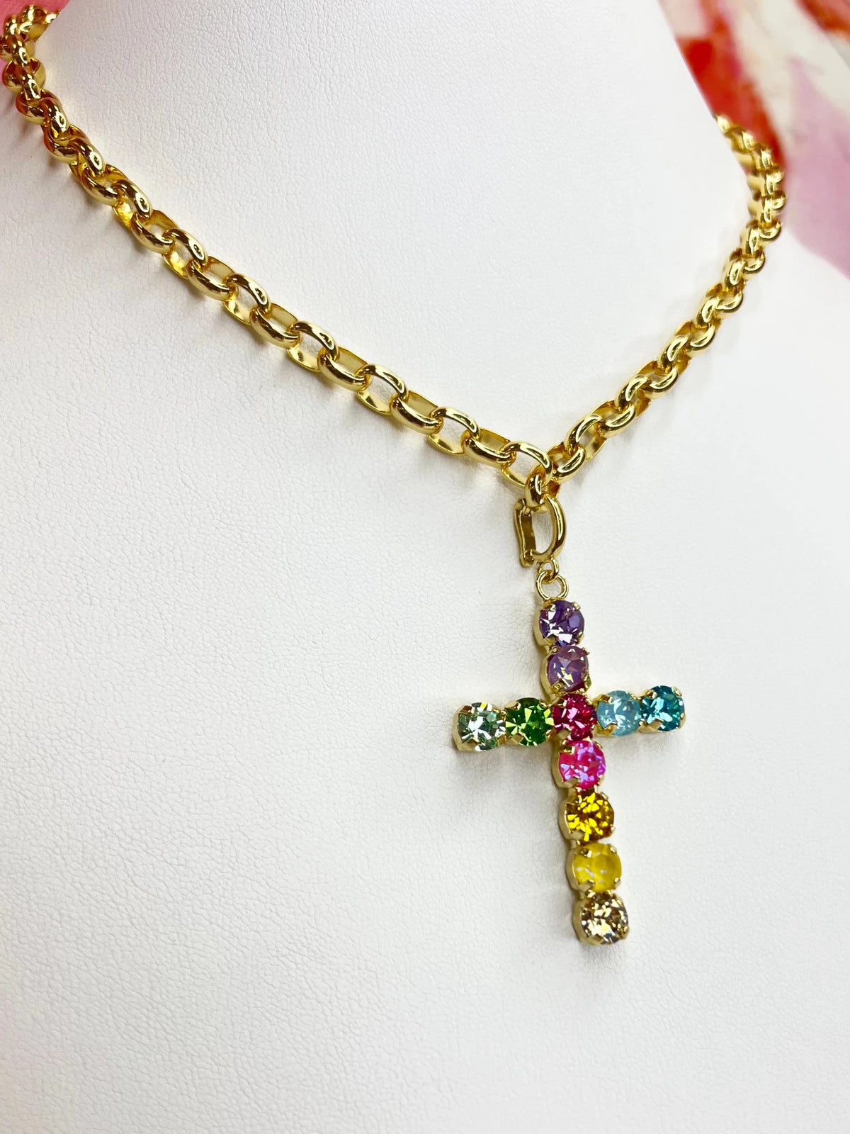 Cross pendant hanging from a strand of multicolor crystals