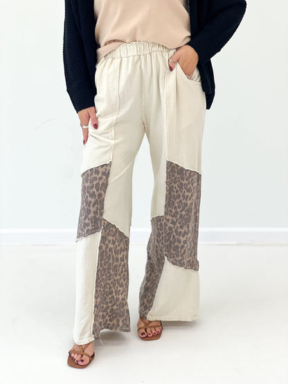 Cream wide-leg pants with leopard print patch at hem, elastic waist and roomy fit