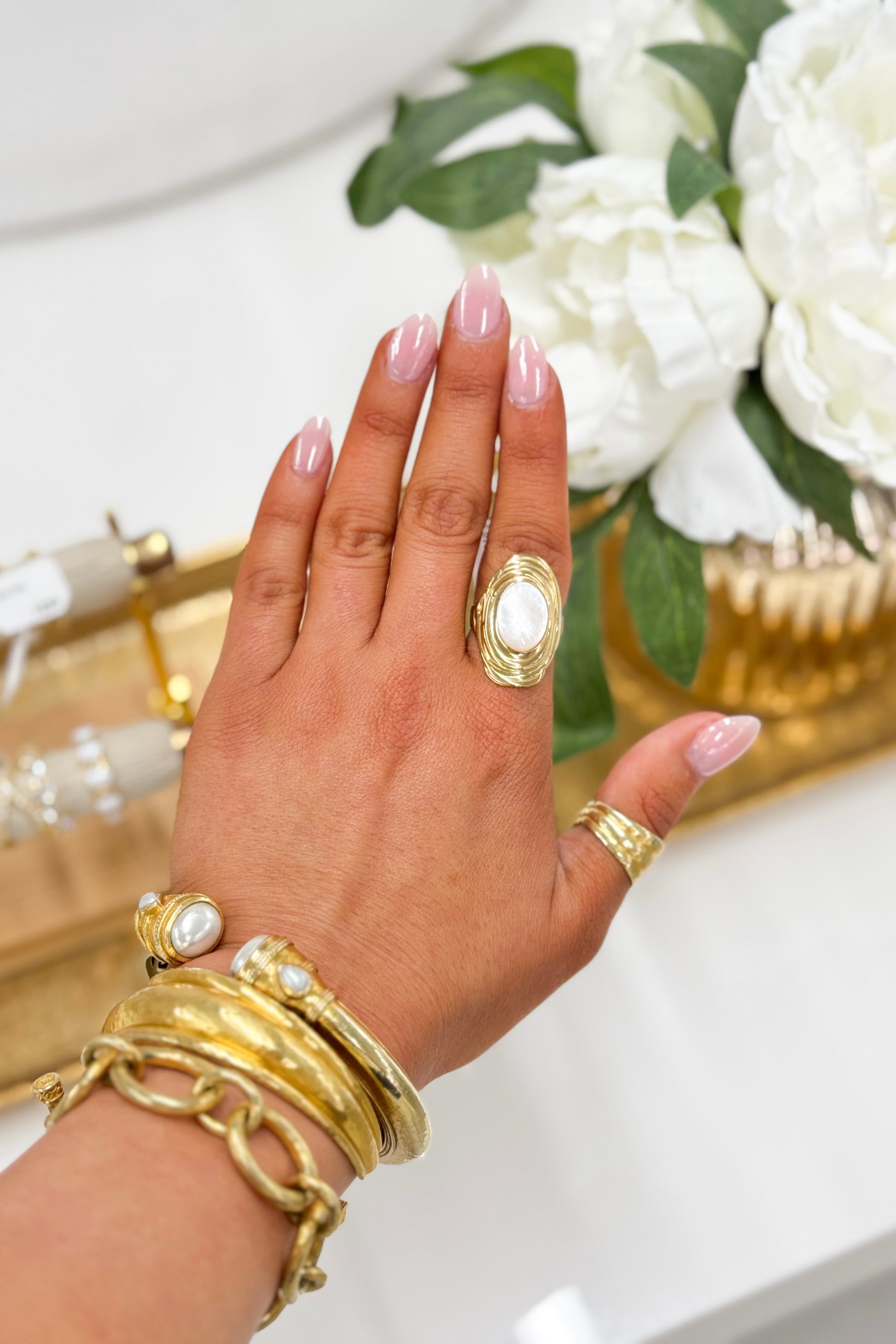 Gold-tone oval moonstone ring with white stone on a hand