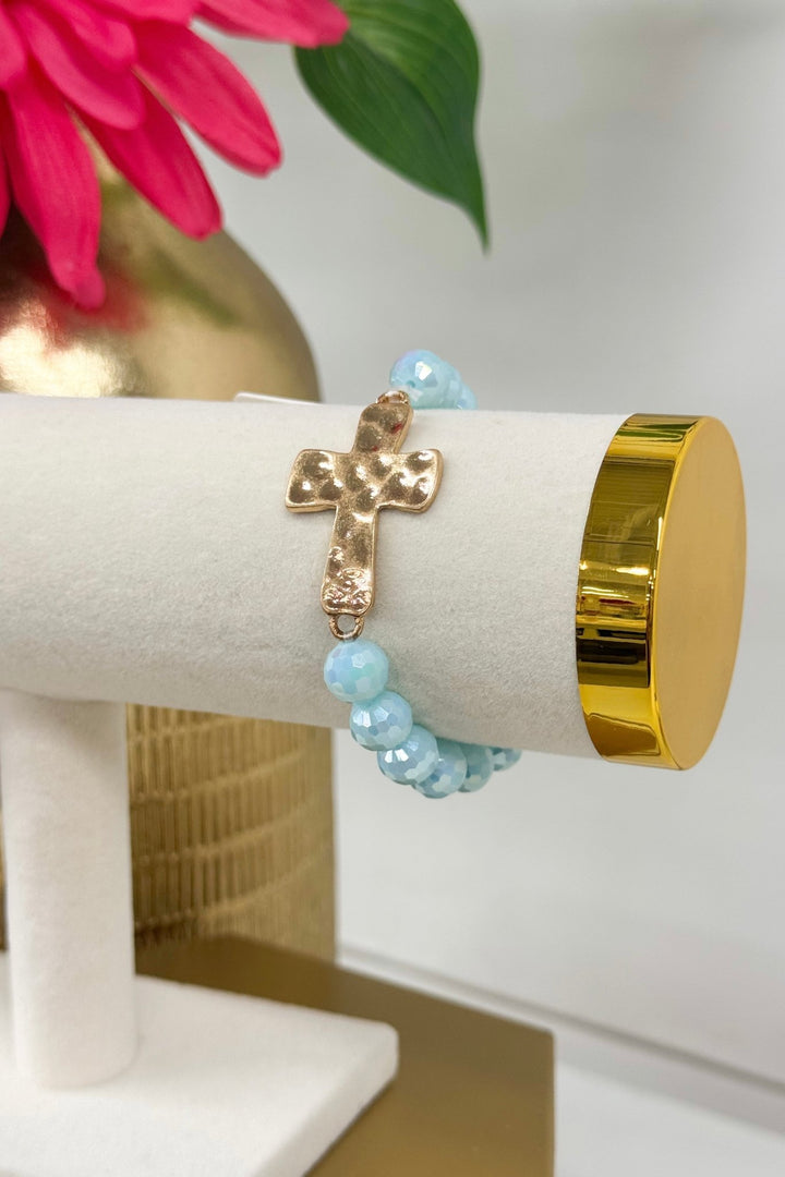 Light blue beaded bracelet with a gold cross charm