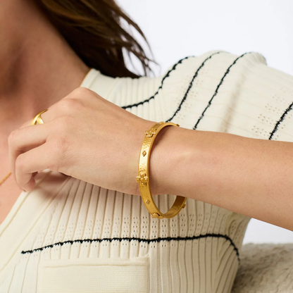 Gold-tone open bangle bracelet on wrist with repeating cross details
