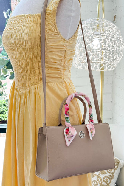 Beige crossbody purse with a decorative scarf accent