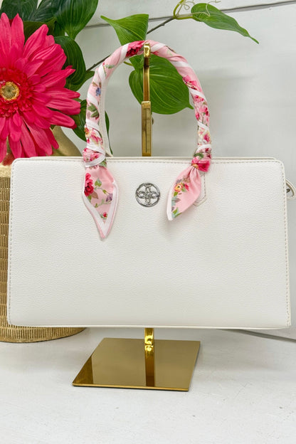White crossbody bag with a scarf tied to the strap