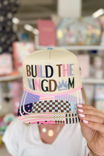 Cap with 'Build the Kingdom' text held by a person in a store setting