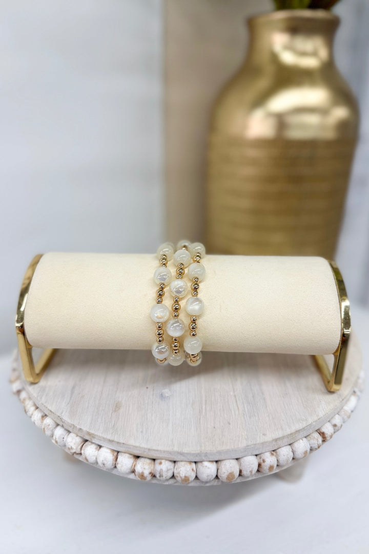 Three-row bracelet of white beads and gold balls