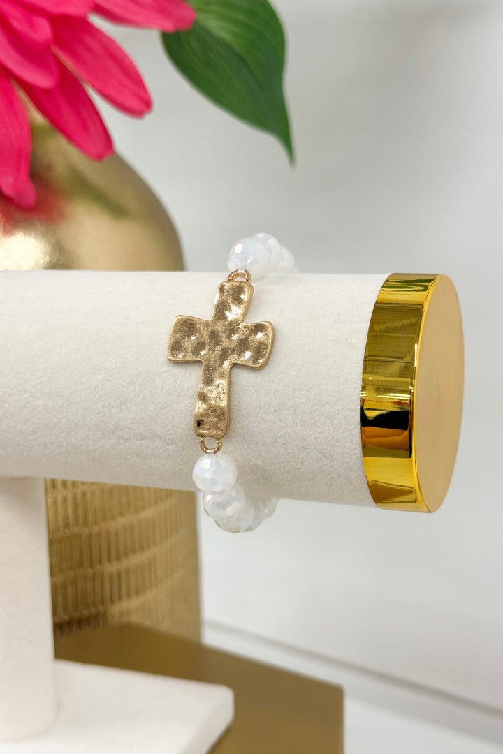 White beaded bracelet with a gold cross charm