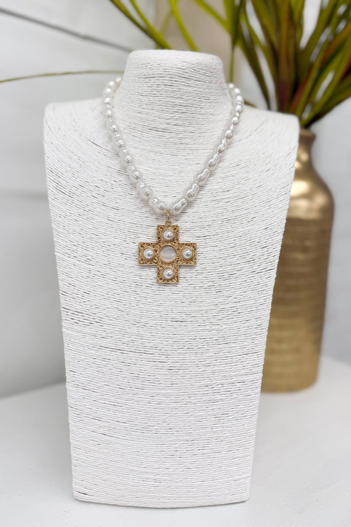 White pearl necklace with a gold cross pendant