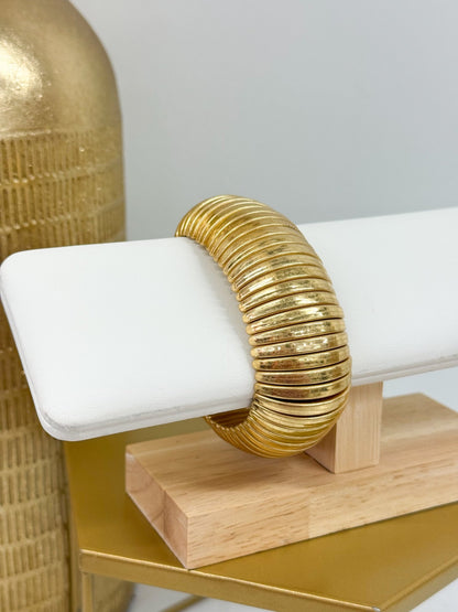 Broad metal bangle with an aged gold finish