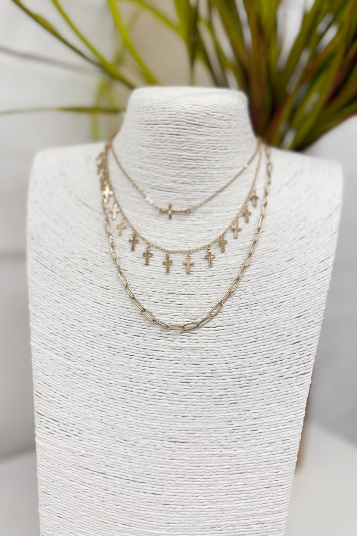 Worn gold necklace with multiple cross charms